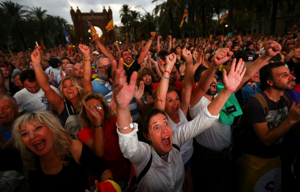 People react as they watch a sesion of the Catalonian regional parliament on a giant screen at a pro-independence rally in Barce