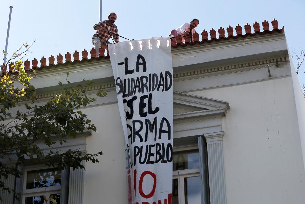Employees of the Spanish embassy remove a banner hung by self-proclaimed anarchists in favor of Catalonian independence, seen at