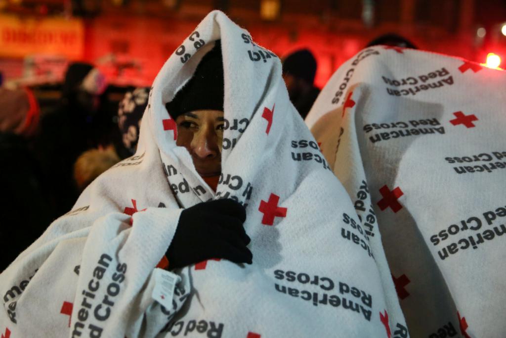 Evacuees wear blankets as they stand after a fire at an apartment building in Bronx